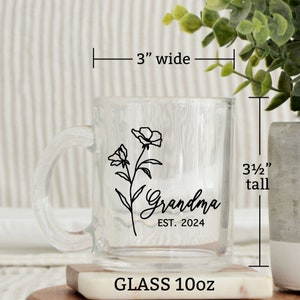 May include: A clear glass mug with a black floral design and the text "Grandma Est. 2024". The mug is 3 1/2 inches tall and 3 inches wide. It is a 10oz glass mug.