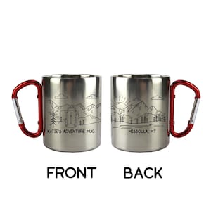 Puede incluir: Dos tazas de viaje de acero inoxidable con asas de mosquet&oacute;n rojas. Una taza presenta un gr&aacute;fico de monta&ntilde;a y mochila con el texto "KATIE'S ADVENTURE MUG". La otra taza tiene un gr&aacute;fico de monta&ntilde;a y amanecer con el texto "MISSOULA, MT".