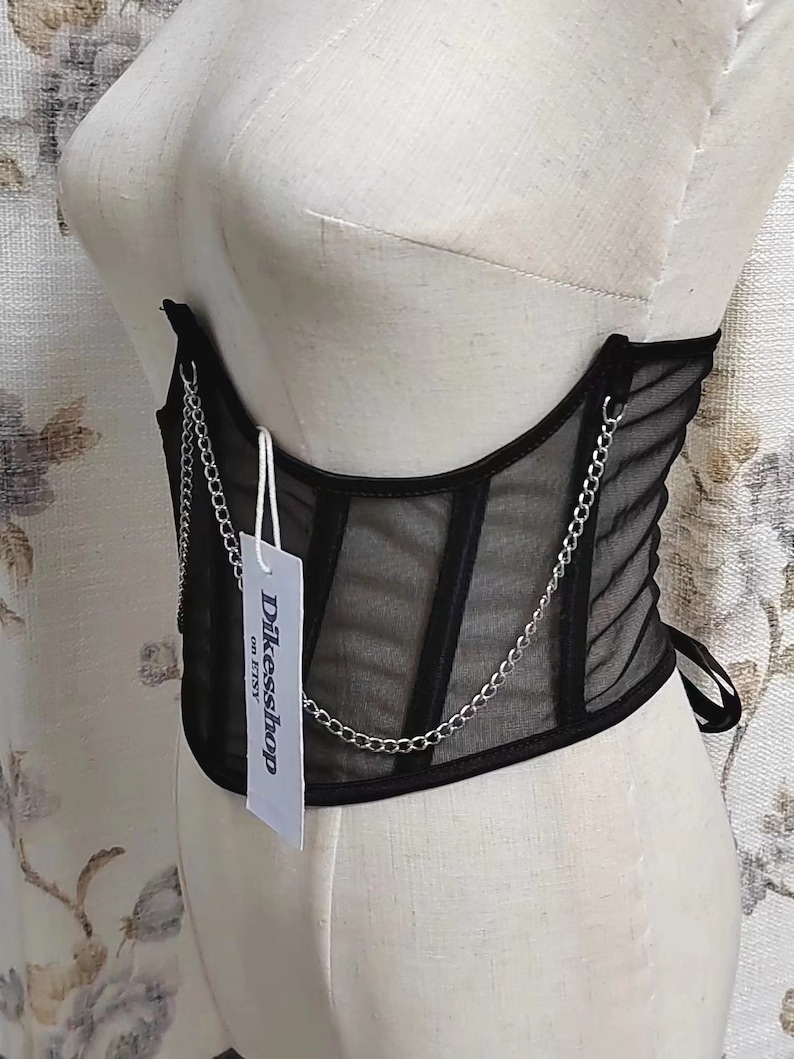 K&ouml;nnte beinhalten: Schwarzes Mesh-Korsett mit silbernem Kettendetail und einem wei&szlig;en Etikett mit der Aufschrift "Dikessshop on Etsy".