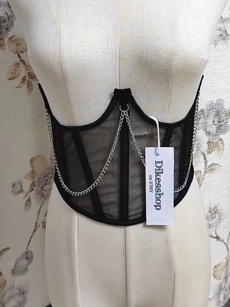 K&ouml;nnte beinhalten: Schwarzes Mesh-Korsett mit silbernen Ketten und einem wei&szlig;en Etikett mit der Aufschrift "Dikeesshop on ETSY".