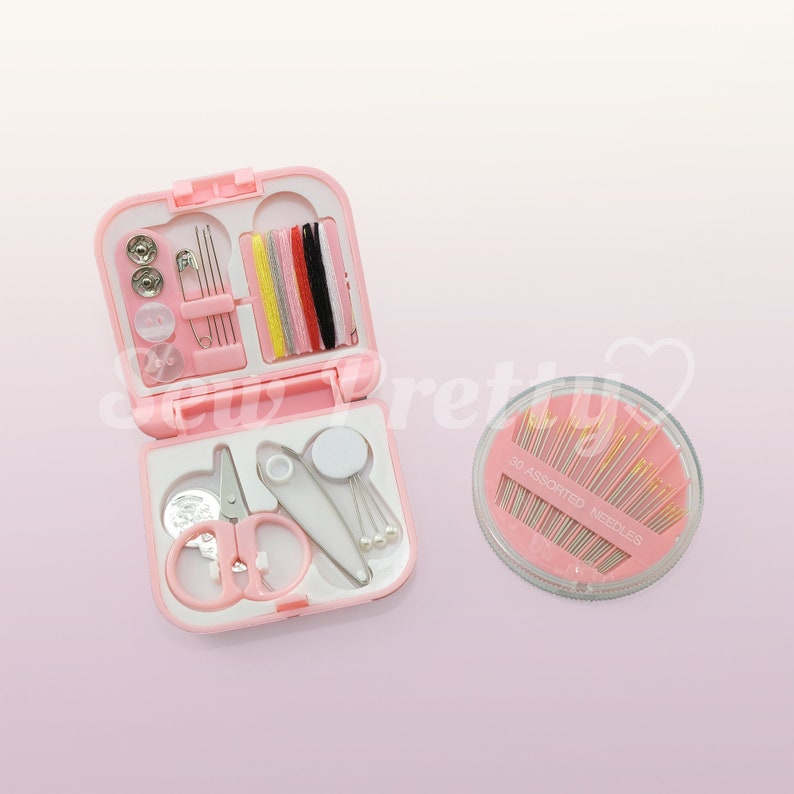 May include: A pink sewing kit with a variety of tools, including needles, thread, buttons, a thimble, and scissors. The kit is open and the contents are visible. There is also a separate container of 30 assorted needles.