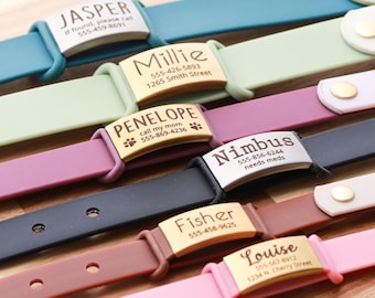 May include: A collection of colorful pet ID collars with engraved nameplates. The collars are in various colors, including teal, green, purple, black, brown, and pink. Each collar has a metal nameplate with a pet's name and contact information.