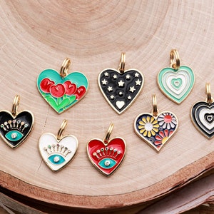 May include: Eight gold heart-shaped charms with different enamel designs. The charms feature a variety of colors and patterns, including red, green, black, white, and blue. The charms are perfect for adding a touch of personality to jewelry or keychains.