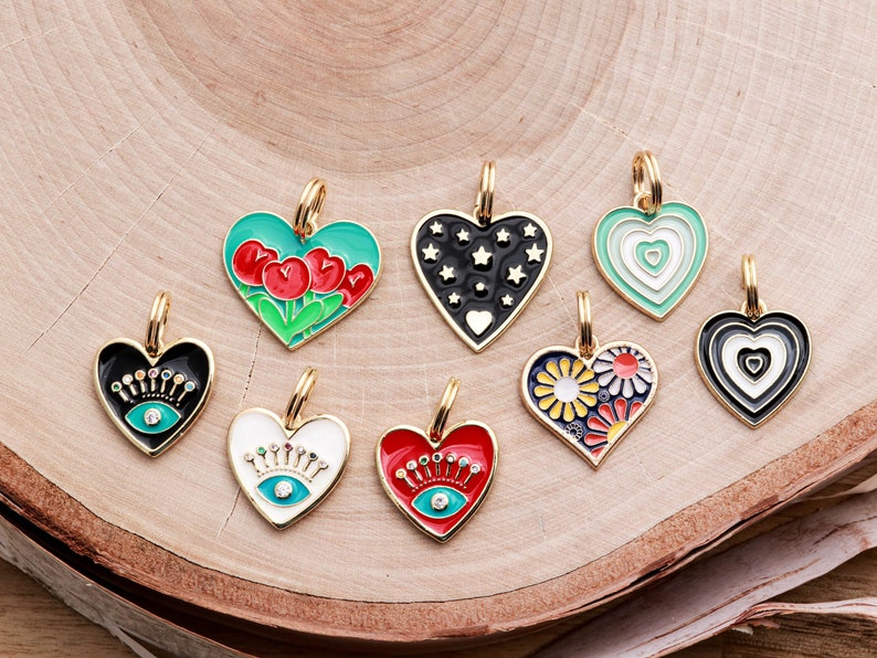 May include: Eight gold heart-shaped charms with different enamel designs. The charms feature a variety of colors and patterns, including red, green, black, white, and blue. The charms are perfect for adding a touch of personality to jewelry or keychains.