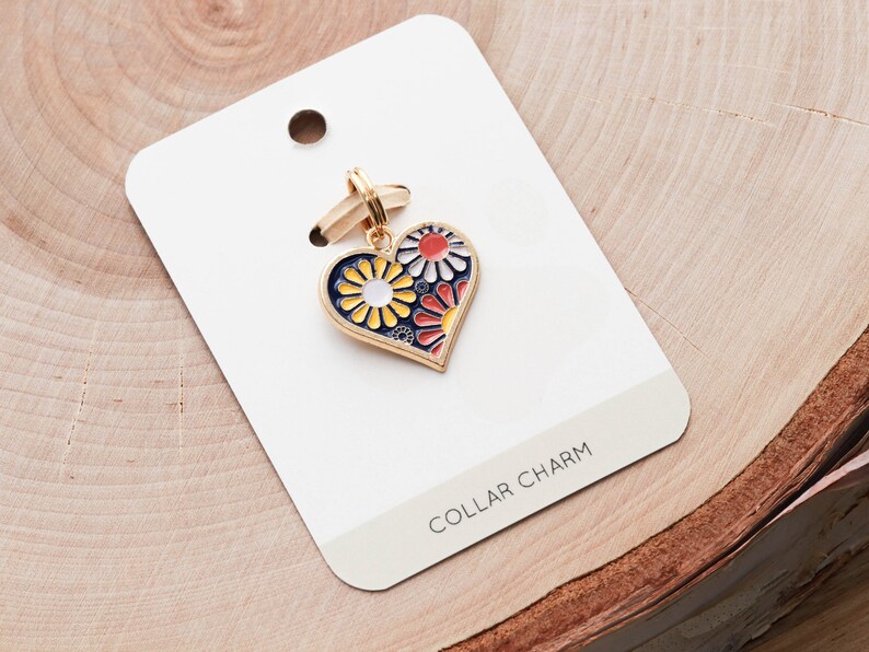May include: Gold heart-shaped collar charm with a blue enamel background and colorful floral design. The charm is on a white card with the text "COLLAR CHARM".