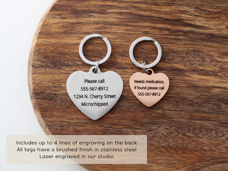 May include: Two heart-shaped pet ID tags with key rings. The silver tag reads "Please call 555-567-8912 1234 N. Cherry Street Microchipped". The rose gold tag reads "Needs medication, If found please call 555-567-8912".