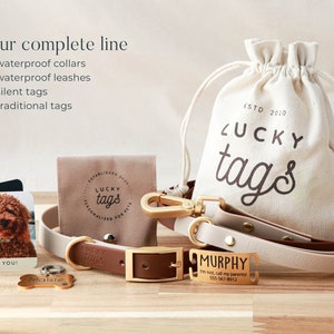May include: A set of dog accessories from Lucky Tags, including a brown leather collar with a gold buckle, a beige and brown leather leash with a gold clasp, a gold dog tag with the name "Murphy" engraved on it, and a small brown pouch with the Lucky Tags logo. The pouch is made of canvas and has a drawstring closure. The text "ESTD 2010" is printed on the pouch.