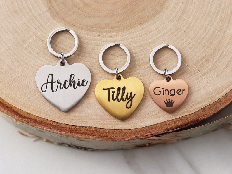 May include: Three heart-shaped keychains with engraved names: Archie, Tilly, and Ginger. The Ginger keychain has a small crown engraved below the name.