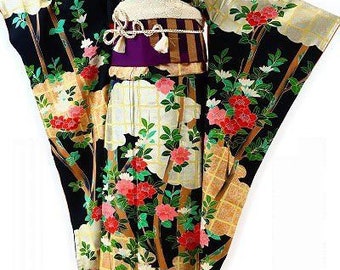 May include: A traditional Japanese kimono with a black background, adorned with vibrant red and pink floral patterns, green leaves, and gold accents. The kimono features a white obi belt with a purple sash and is displayed on a mannequin.