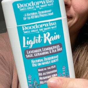 May include: White deodorant stick with a teal label. The label reads "Deodorwise Light Rain" with ingredients listed. It states "Natural Deodorant Use on Whole Body!" and "Made in the USA!"