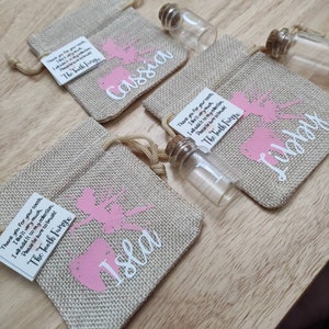 May include: Three small hessian bags with pink fairy silhouettes and the names Cassia, Isla, and Libby printed on them. Each bag contains a small glass vial and a note that reads "Thank you for your tooth, I like it very much. I will add it to my collection. Please be sure to brush! The Tooth Fairy".