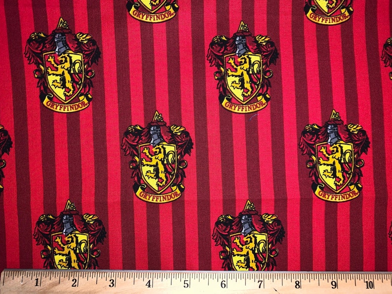 May include: Red and gold fabric with a repeating pattern of the Gryffindor house crest from the Harry Potter series. The crest features a lion, a shield, and the words "Gryffindor" in a banner.