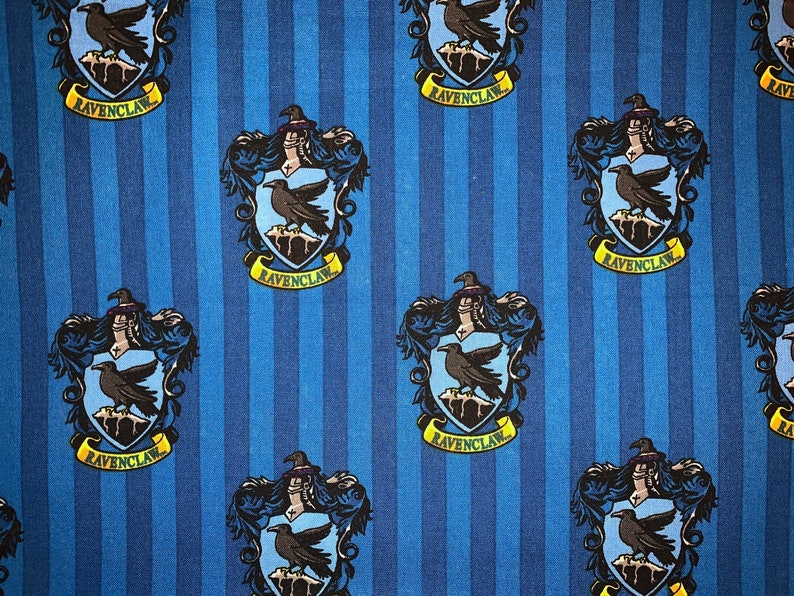 May include: Blue and yellow fabric with a repeating pattern of the Ravenclaw house crest from the Harry Potter series. The crest features a raven and the words "Ravenclaw" on a banner.