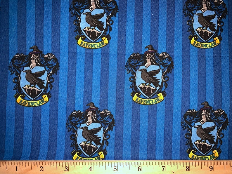 May include: Blue and yellow fabric with a repeating pattern of the Ravenclaw house crest from the Harry Potter series. The crest features a raven, a wizard's hat, and the words "Ravenclaw".