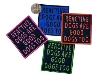 May include: Four embroidered patches with the text "REACTIVE DOGS ARE GOOD DOGS TOO". The patches are in various colors: pink, blue, orange, and green. The patches are square or rectangular with a black background.
