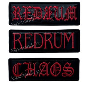 May include: Three black rectangular patches with red embroidered text. The top two patches read "REDRUM" in a gothic font. The bottom patch reads "CHAOS" in a similar font. The patches have a glossy finish.