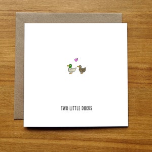 May include: A white card with a brown envelope. The card has a simple illustration of two ducks facing each other with a pink heart above them. The text "TWO LITTLE DUCKS" is printed below the illustration.