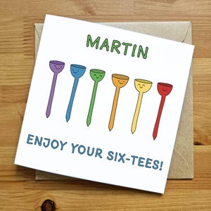 May include: A white card with the name "MARTIN" written in green letters.  The card has a colorful illustration of six golf tees with smiley faces. The text "ENJOY YOUR SIX-TEES!" is written in blue letters.