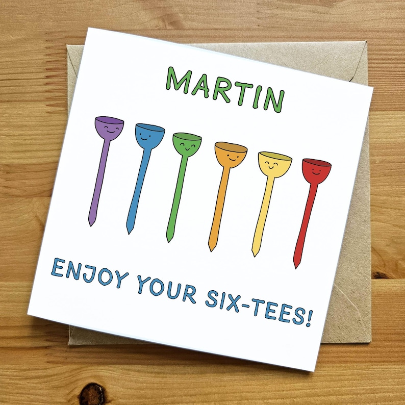 May include: A white card with the name "MARTIN" written in green letters.  The card has a colorful illustration of six golf tees with smiley faces. The text "ENJOY YOUR SIX-TEES!" is written in blue letters.