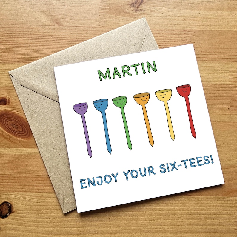 May include: A white card with the name "MARTIN" written in green text. The card has a rainbow of six golf tees with smiley faces on them. The text "ENJOY YOUR SIX-TEES!" is written in blue text at the bottom of the card.