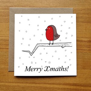 May include: A white Christmas card featuring a red robin perched on a branch. The robin has a red breast and a grey head. The background is white with small black squares and triangles. The card reads "Merry Xmaths!" in black cursive writing.