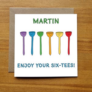 May include: A white card with the name "MARTIN" printed in green letters.  Below the name are six colorful golf tees with smiley faces. The text "ENJOY YOUR SIX-TEES!" is printed in blue letters below the golf tees.
