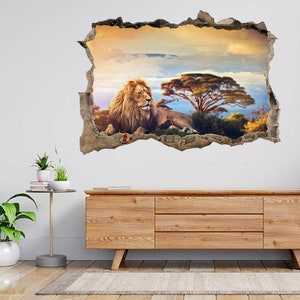Pode incluir: Um adesivo de parede 3D que apresenta um leão deitado em uma paisagem de savana com uma grande árvore e um céu nublado. O adesivo é projetado para parecer que a parede foi rompida, revelando a cena atrás.