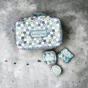 May include: A blue and white patterned fabric sewing case with a label that says "My Sewing Case". There are three smaller fabric boxes with labels that say "Stitched with Love", "Needles", and "Measure Twice".