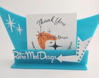 May include: A turquoise acrylic display stand with a pointed, star-shaped cutout design. The front features a white arrow and the text Retro Mod Design. A white card is tucked inside, printed with Thank You, Retro Mod Designs, and star graphics.