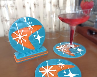 May include: Set of three turquoise and orange coasters with a mid-century modern design featuring a boomerang shape and white stars.