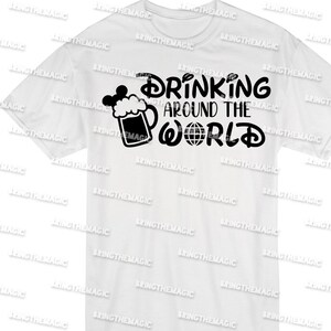 Puede incluir: Camiseta blanca con un dise&ntilde;o gr&aacute;fico negro que dice "Drinking Around the World" con una jarra de cerveza y un globo terr&aacute;queo. La jarra de cerveza tiene una oreja de Mickey Mouse en la parte superior.