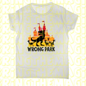 Puede incluir: Camiseta blanca con una silueta negra de un dinosaurio frente a un castillo con el texto "WRONG PARK" debajo.