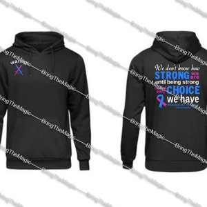 May include: Black hoodie with a pink and blue crossed swords graphic on the front and a message on the back that reads "We don't know how STRONG we are until being strong is our only CHOICE we have. Rheumatoid Arthritis Awareness."