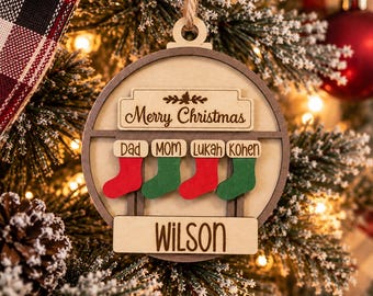 Può includere: Una decorazione natalizia rotonda in legno con la scritta Merry Christmas in alto e il nome WILSON in basso. Quattro piccole calze in legno, alternate nei colori rosso e verde, riportano i nomi DAD, MOM, LUKAH e KOHEN incisi sopra.