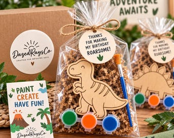 Può includere: Un sacchetto di plastica trasparente riempito con carta marrone stropicciata, una sagoma in legno di T-Rex, un pennello blu e tre piccoli vasetti di vernice verde, arancione e blu. Un'etichetta rotonda recita "THANKS FOR MAKING MY BIRTHDAY ROARSOME!" con un'impronta.