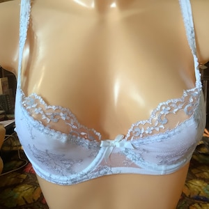 Puede incluir: Sujetador de encaje blanco con delicado bordado floral y tirantes ajustables.