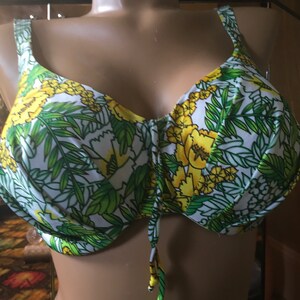 May include: A white, green, and yellow floral print bikini top with adjustable straps and a tie closure at the front.