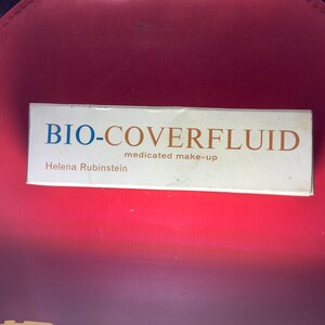 Könnte beinhalten: Eine weiße Schachtel mit dem Aufdruck "BIO-COVERFLUID medicated make-up Helena Rubinstein".