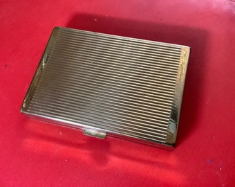 Könnte beinhalten: Ein silbernes Zigarettenetui mit einem gerippten Design.