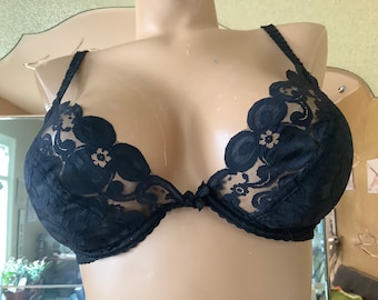 Pode incluir: Sutiã de renda preta com detalhes florais. O sutiã tem um design delicado e feminino.