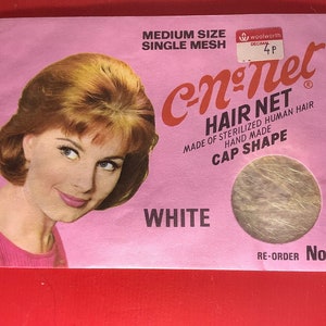 Könnte beinhalten: Eine rosa und weiße Verpackung für ein Haarnetz. Die Verpackung zeigt eine Frau mit blonden Haaren und eine Nahaufnahme des Haarnetzes. Der Text auf der Verpackung lautet "c-n-net Hair Net Made of Sterilized Human Hair Hand Made Cap Shape White Re-Order No. 1"