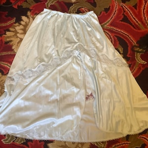 May include: A light blue satin slip skirt with lace trim. The skirt has a slit up the front and is a full length.