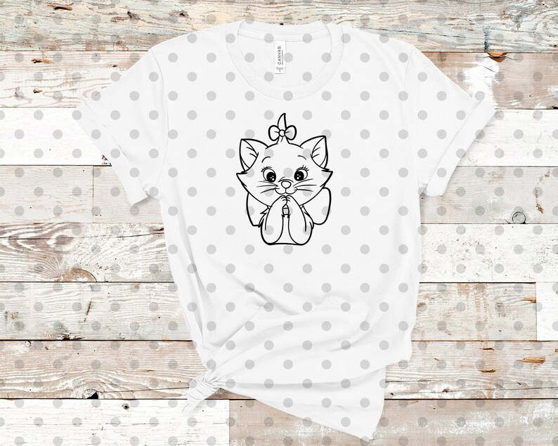 May include: White t-shirt with a black and white outline of a cartoon cat with a bow on its head. The cat is wearing a bow tie and has its paws clasped together. The t-shirt has a white background with small black polka dots.