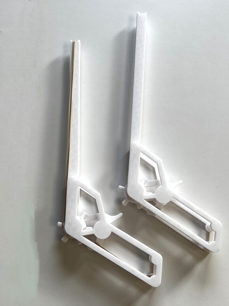 May include: Two white plastic bookends shaped like a construction vehicle. The bookends are angled and have a cutout design of a vehicle with wheels.