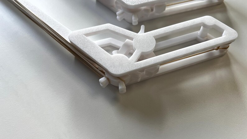 May include: White plastic clips with a gold metal spring. The clips are designed to hold items together.