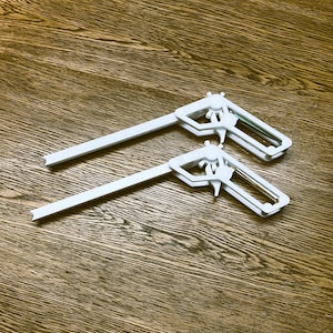May include: Two white plastic corner clamps, designed to hold pieces of wood together at a 90-degree angle.