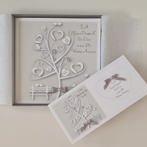 May include: A white card with a gray background and a white paper cut-out tree with hearts. The card says "To A Special Daughter & Son In Love On Your 25th Wedding Anniversary".