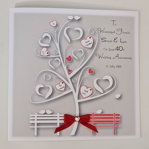 May include: A wedding anniversary card with a gray background features a white tree design with heart-shaped leaves and red accents. The card includes the text "To Wonderful Friends Stuart & Lynn On Your 40th Wedding Anniversary 5 July 1981."