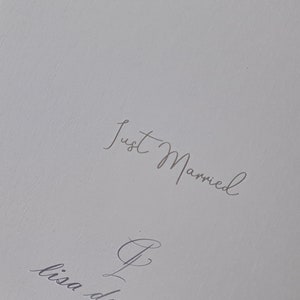May include: A white card with the text "Just Married" in gray script. The card also has the text "Lisa Donald Creative" and a website address.