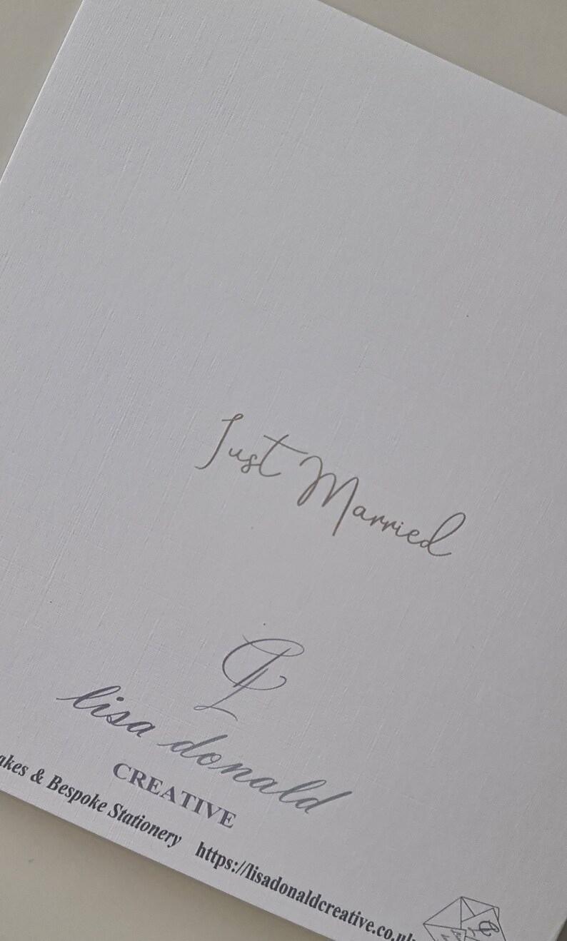May include: A white card with the text "Just Married" in gray script. The card also has the text "Lisa Donald Creative" and a website address.